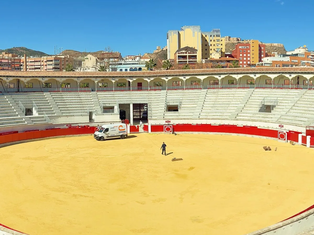 La plaza de toros de Lorca vista desde arriba, con el ruedo amarillo y el cielo azul
